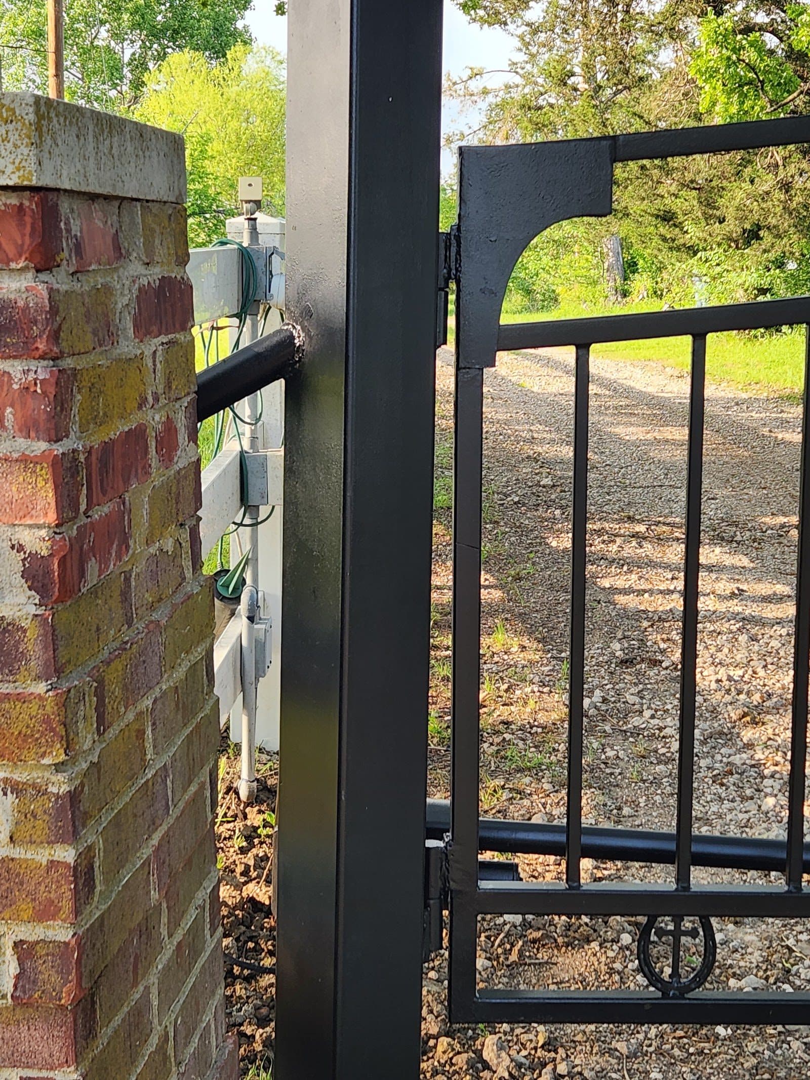 Decorative plasma cut steel gate panel being installed on brick columns
